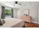 Well-lit bedroom with hardwood floors, ceiling fan, natural light, and stylish dresser at 1022 Carolina Ave, Durham, NC 27705