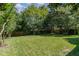 Green back yard features short cut grass and trees surrounding the yard and a wood fence at 103 Equestrian Ct, Cary, NC 27513