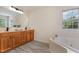 Bathroom featuring a soaking tub, oak cabinets, and a large mirror at 103 Equestrian Ct, Cary, NC 27513