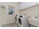 Functional laundry room with modern washer and dryer, ample storage cabinets, and a utility sink for convenience at 103 Equestrian Ct, Cary, NC 27513