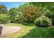 Landscaped backyard with lush green grass, stone patio, and mature trees and shrubs at 107 Sonoma Valley Dr, Cary, NC 27518