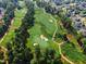 Aerial view of the golf course and surrounding neighborhood with tree lined streets at 108 Ribbon Walk Ln, Holly Springs, NC 27540