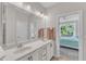 Bright bathroom with double sinks, a large mirror, and a doorway view into the primary bedroom at 108 Ribbon Walk Ln, Holly Springs, NC 27540