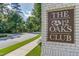 Welcoming entrance sign to the 12 Oaks Club community, framed by lush greenery and a neatly paved road at 108 Ribbon Walk Ln, Holly Springs, NC 27540