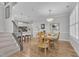Bright dining room with wood floors, staircase, dining table and chairs, and decorative light fixture at 108 Ribbon Walk Ln, Holly Springs, NC 27540