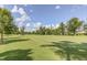 View of the lush green golf course with mature trees on a partly cloudy day at 108 Ribbon Walk Ln, Holly Springs, NC 27540