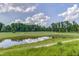Scenic view of the golf course with a tranquil pond and lush green fairway on a partly cloudy day at 108 Ribbon Walk Ln, Holly Springs, NC 27540