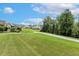 Serene backyard showcasing a grassy lawn, mature trees, and neighborhood homes in the distance at 149 Ivory Ln, Raleigh, NC 27610