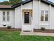 Close-up of the home's entrance, featuring a black door and well-maintained landscaping at 1709 Hawthorne Lane Ln, Burlington, NC 27215