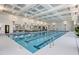 Bright indoor swimming pool with lane markers, decorative lighting and large windows with seating at 173 Churchill Way, Clayton, NC 27520