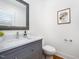Stylish half bath with a marble vanity, toilet and framed floral art at 200 W Corbin St, Hillsborough, NC 27278