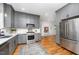 Beautiful kitchen features gray cabinets, stainless appliances, quartz countertops, and hardwood flooring at 200 W Corbin St, Hillsborough, NC 27278