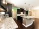 Modern kitchen featuring granite countertops, a spacious island, stainless steel appliances, and dark wood cabinetry at 2008 Campana Dr, Raleigh, NC 27603