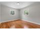 Bright bedroom featuring hardwood flooring, a light fixture, and multiple windows overlooking the yard at 202 Purvis St, Garner, NC 27529
