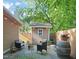 Backyard stone patio area with chairs, fire pit, shed, privacy fence, and string lights overhead at 211 W Trinity Ave, Durham, NC 27701