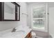 Bright bathroom with a white sink, wood vanity, mirror, and window at 2208 Pathway Dr, Chapel Hill, NC 27516