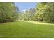 Expansive backyard featuring a lush green lawn and mature trees offers ample space for recreation and relaxation at 2406 Oxford Rd, Raleigh, NC 27608