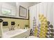 Bathroom featuring a yellow and grey shower curtain, matching tile and an artful mirror at 2406 Oxford Rd, Raleigh, NC 27608