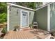 Cozy entryway with light gray front door, wood porch, potted flowers, and charming exterior lights at 2410 Huron St, Durham, NC 27707