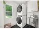 Functional laundry room with stackable washer and dryer, stainless steel sink, and black hexagon tile floor at 2410 Huron St, Durham, NC 27707