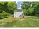 Backyard storage shed surrounded by green grass and lush trees at 2410 Huron St, Durham, NC 27707