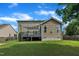 Home exterior with a gray deck, lush green lawn, and mature trees under a blue sky at 2605 Bloomsberry Ridge Dr, Fuquay Varina, NC 27526