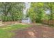 Spacious backyard featuring a partial fence, grassy areas, and mature trees, offering privacy at 301 N King Charles Rd, Raleigh, NC 27610