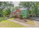 Quaint, red brick home featuring a welcoming front porch, green siding and mature landscaping at 301 N King Charles Rd, Raleigh, NC 27610