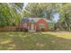 Charming home features a brick facade, green siding, mature trees, and a well-maintained lawn at 301 N King Charles Rd, Raleigh, NC 27610
