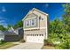 Front view of a two story home with a two car garage and a mix of siding and shingles, nestled between mature trees at 304 Garden Walk Dr, Durham, NC 27703