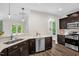 Bright kitchen with stainless steel appliances, dark wood cabinets, and modern light fixtures at 304 Garden Walk Dr, Durham, NC 27703