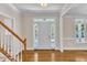 Bright foyer with hardwood floors, staircase, and sidelight windows surrounding the front door at 305 Avent Meadows Ln, Holly Springs, NC 27540