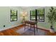 Bright bedroom features hardwood floors, neutral paint, and two windows overlooking mature trees at 3213 Mid Pines Rd, Raleigh, NC 27606