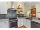 Kitchen with stainless appliances, gray tile backsplash, and floating wood shelves at 3213 Mid Pines Rd, Raleigh, NC 27606