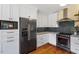 Kitchen with stainless appliances, gray tile backsplash, and white cabinets at 3213 Mid Pines Rd, Raleigh, NC 27606