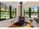 Living room featuring a wood burning stove, large windows with green views, and hardwood floors at 3213 Mid Pines Rd, Raleigh, NC 27606
