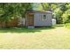 Exterior of grey outbuilding featuring a brown door, window, and trim in a grassy lawn at 3213 Mid Pines Rd, Raleigh, NC 27606