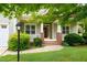 Inviting front porch with brick accents, classic columns, and verdant landscaping at 322 Bellemont Rd, Pittsboro, NC 27312