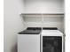 Functional laundry room with modern washer and dryer units under a shelf for storage and organization at 406 Dairy Farm Dr, Hillsborough, NC 27278