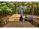 View of outdoor deck with grill, patio table, umbrella, and wooded yard at 406 Dairy Farm Dr, Hillsborough, NC 27278