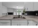 Stainless steel sink and faucet compliment the white cabinetry and grey countertops in this kitchen at 4536 Sugarbend Way, Raleigh, NC 27606