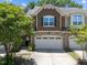 Inviting townhome features a stone accent, a two car garage, and mature landscaping at 469 Methven Grove Dr, Cary, NC 27519