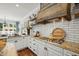 A bright kitchen with white cabinets, granite countertops, stainless steel appliances, and a wood range hood at 4725 Saratoga Falls Ln, Raleigh, NC 27614