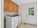 Functional laundry room showcasing wooden cabinets, a new washer and dryer, and access to the backyard at 4816 Marlborough Way, Durham, NC 27713