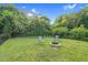 Green backyard featuring chairs, a fire pit, lush landscaping and the Wendel Water Tower in the distance at 527 N Cypress St, Wendell, NC 27591