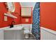 Bright bathroom with red walls, gray vanity, modern fixtures, blue shower curtain, toilet and white trim at 527 N Cypress St, Wendell, NC 27591