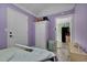Bright bedroom featuring light purple walls, white trim, wood-look floors, closet, and access to kitchen space at 527 N Cypress St, Wendell, NC 27591
