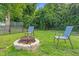 Relaxing backyard featuring a fire pit, lounge chairs, green grass, and a partially fenced yard at 527 N Cypress St, Wendell, NC 27591