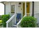 Close-up of a quaint front porch with a bright yellow door and decorative plants at 527 N Cypress St, Wendell, NC 27591