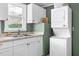 Bright laundry room featuring a stainless steel sink, white cabinets, and a stackable washer and dryer at 527 N Cypress St, Wendell, NC 27591